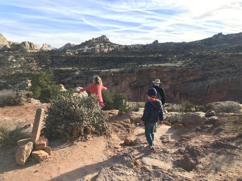 Three people hike along a trail at Capitol Reef National Park.