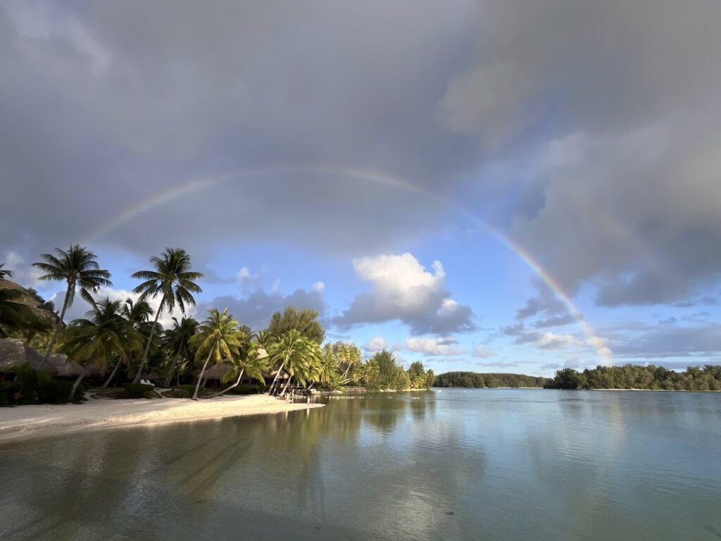 A rainbow over a sandy beach and water in Moorea.